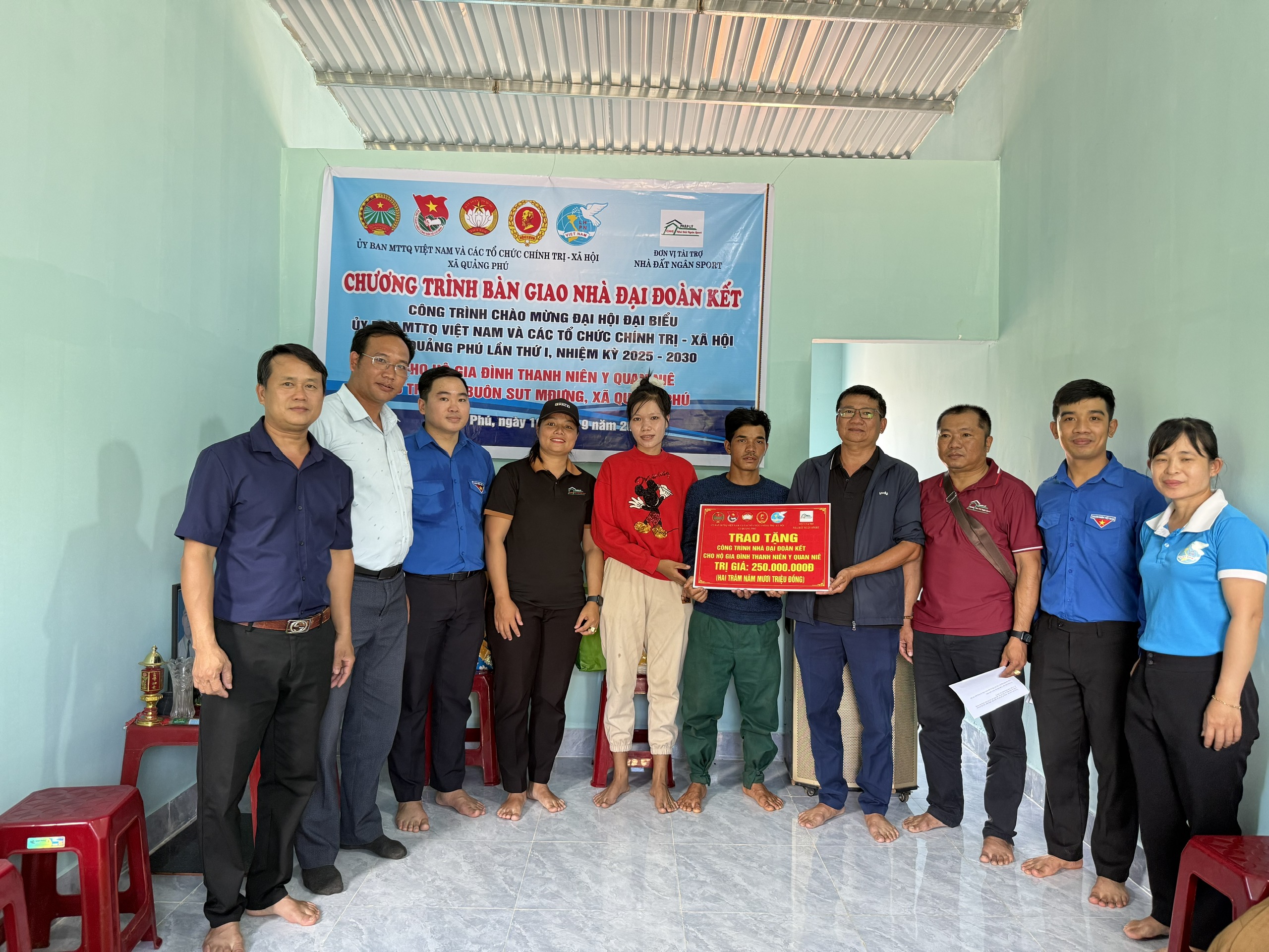 Đại diện chính quyền địa phương, đơn vị tài trợ trai bảng tượng trưng tặng nhà đại đoàn kết cho gia đình anh Y Quan Niê